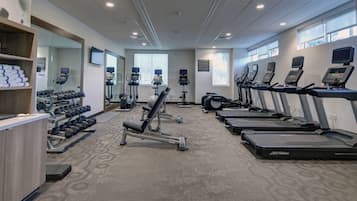 Un gimnàs amb cintes de córrer, pèses i màquines per a musculació.