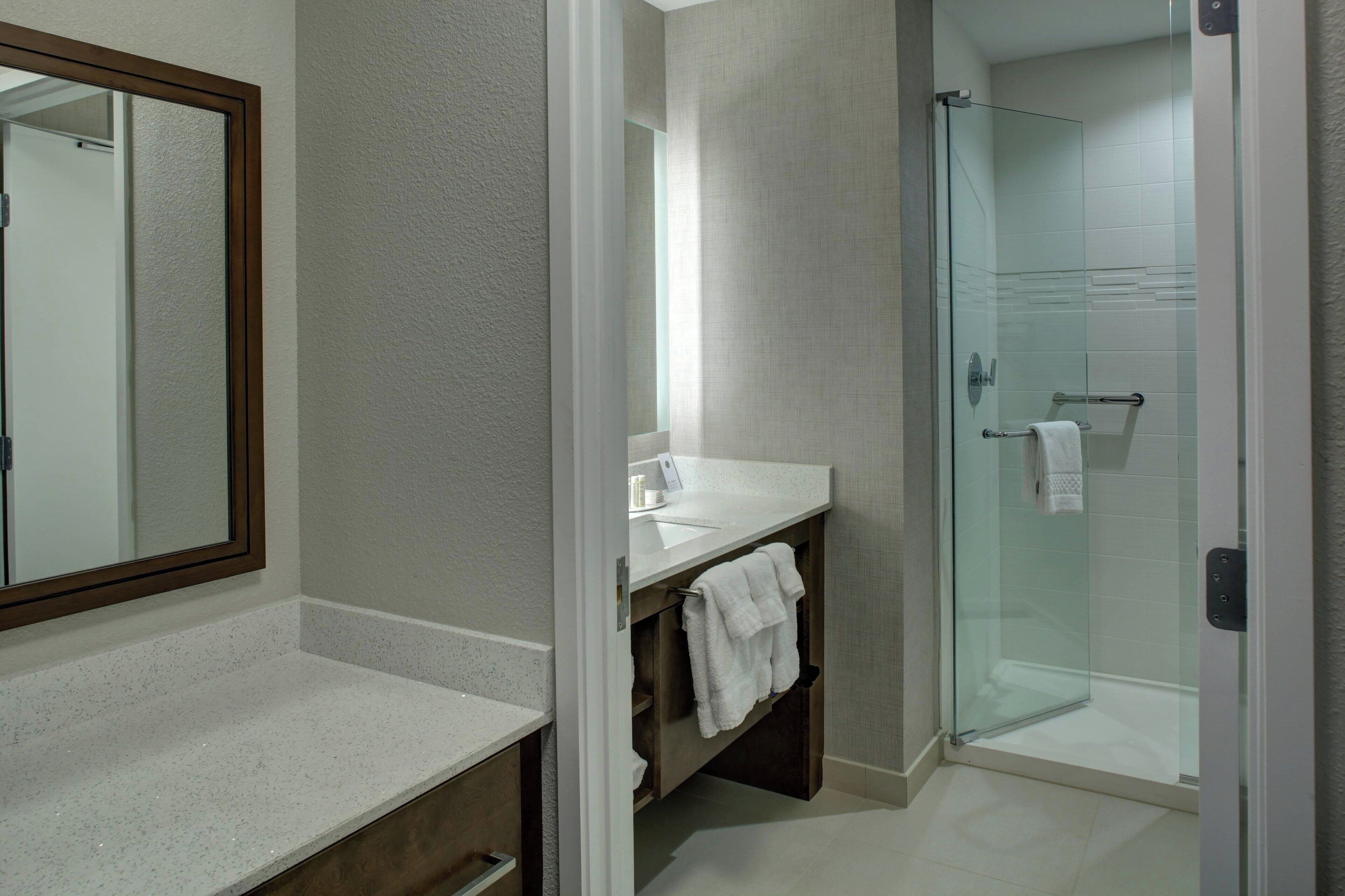 Une salle de bain avec une douche à parois de verre, un lavabo blanc et un miroir.