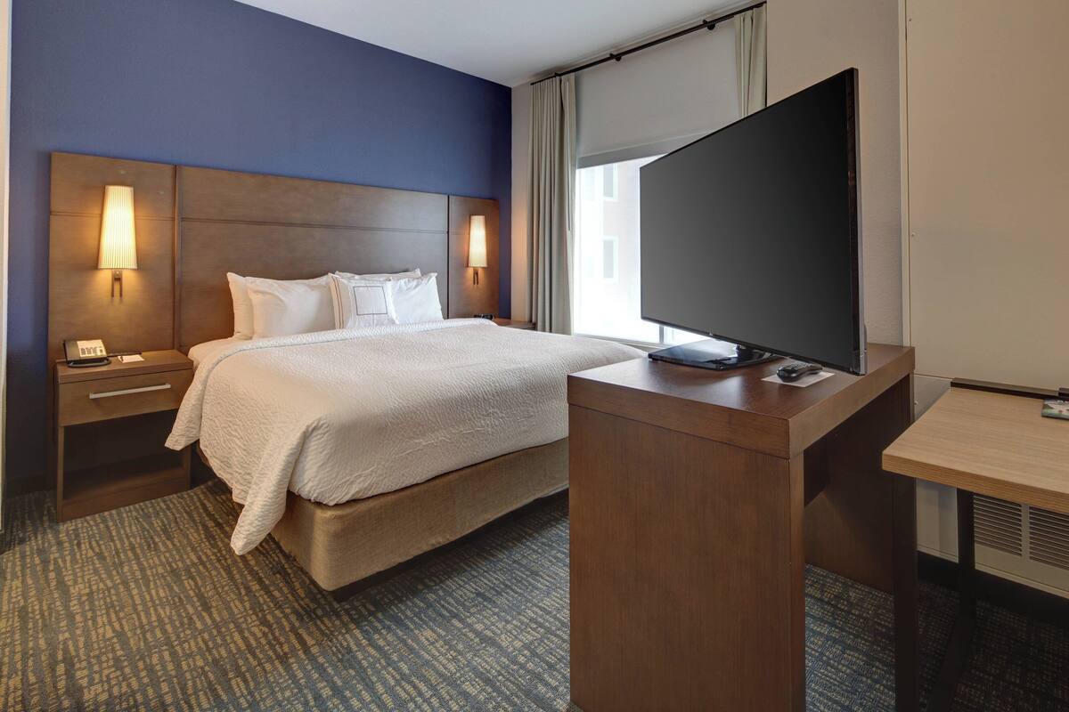 Une chambre d’hôtel avec un grand lit, un bureau doté d’un téléviseur à écran plat et deux lampes de chevet.