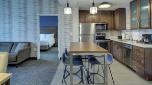 A modern hotel room with a kitchenette, a dining area with bar stools, a sofa, and a bed. - Residence Inn by Marriott Fort Lauderdale Coconut Creek (Coconut Creek)