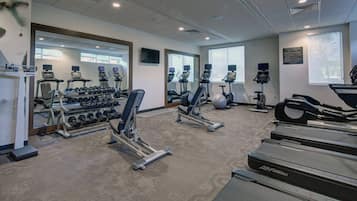 A gym with treadmills, elliptical machines, and free weights.