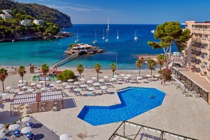 Resort com piscina, área de praia e vista para o mar com barcos.