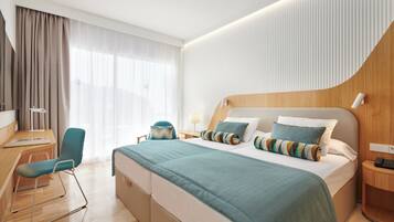 A modern hotel room with a large bed, a desk, and a chair.