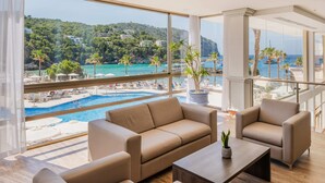 Una sala de estar moderna con un amplio ventanal con vistas a una piscina y una playa.