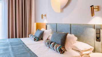 Une chambre d’hôtel avec un grand lit, une tête de lit, une table de chevet et un luminaire fixé au mur.