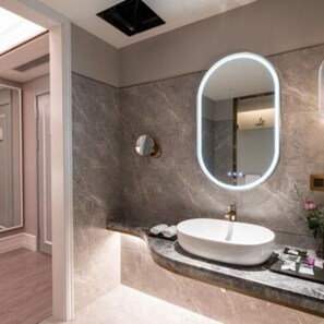 A modern bathroom with a round mirror, a white sink, and a marble countertop.