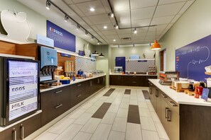 A modern breakfast area with a coffee machine, cereal, and bakery options.