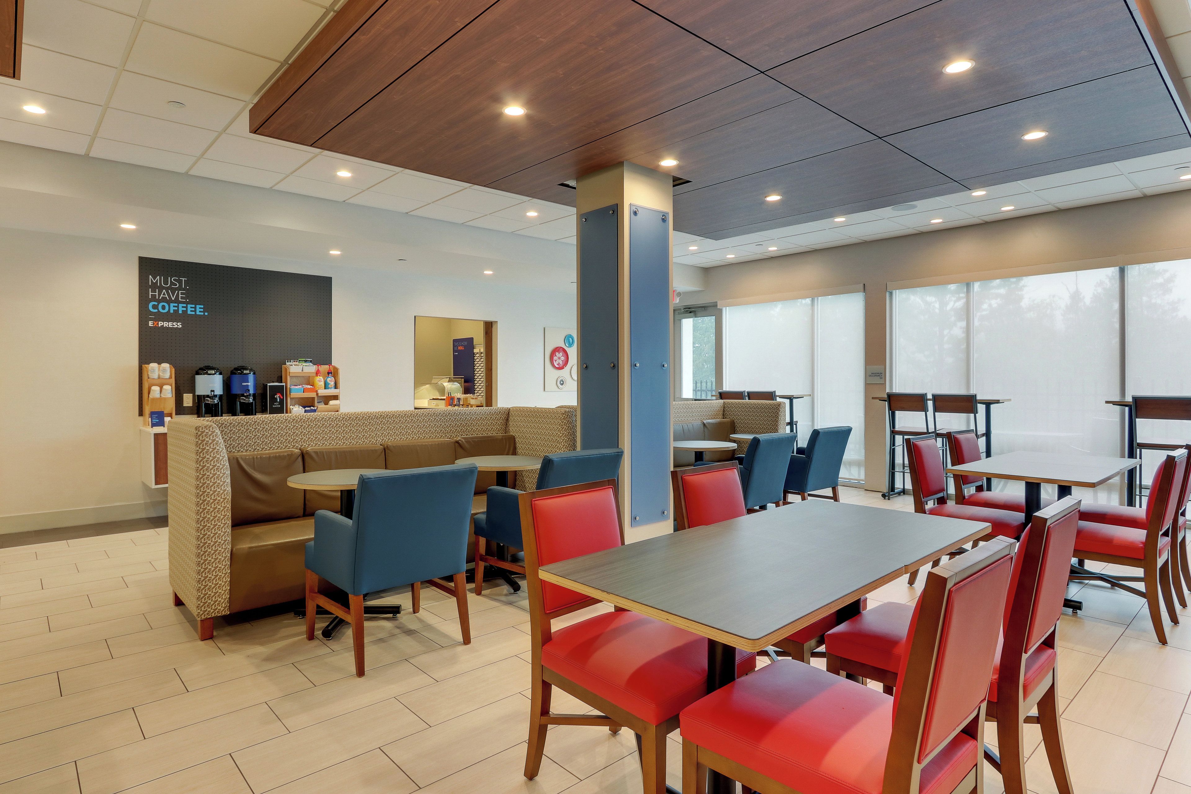 A modern cafe with seating arrangements, a coffee station, and a view through large windows.