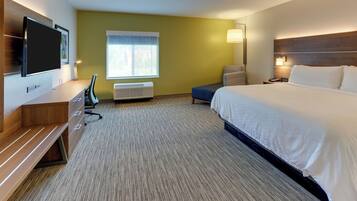 A hotel room with a bed, a desk, a chair, a television, and a window.