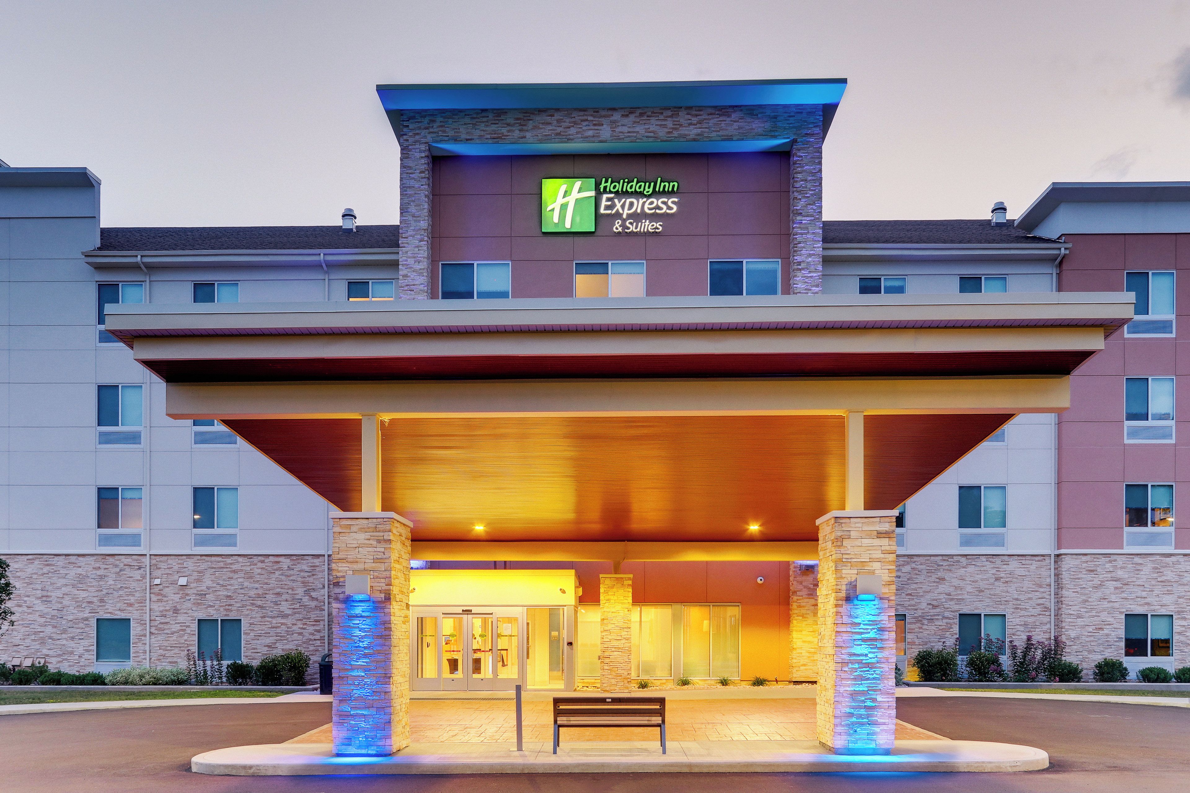 Edificio de Holiday Inn Express & Suites con un acceso cubierto y un banco al frente.