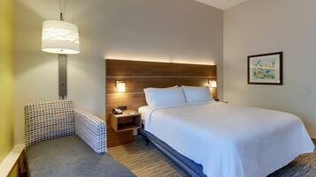 A hotel room with a bed, a nightstand, a telephone, a lamp, and a framed picture on the wall.