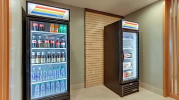 Deux distributeurs automatiques de boissons proposant une variété de produits, notamment de l’eau et des sodas, dans un environnement propre et moderne.