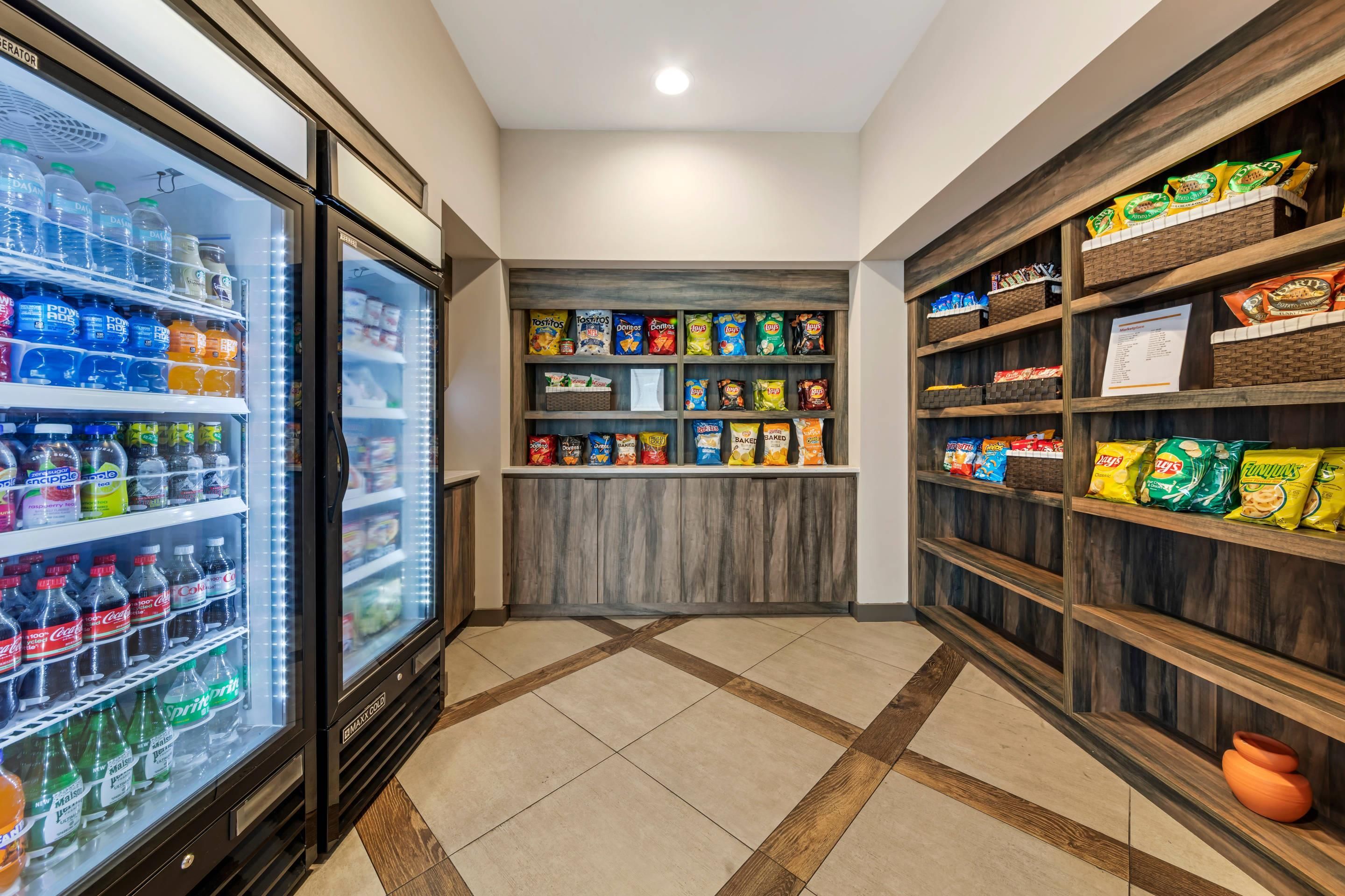 A snack and beverage area with refrigerated drinks, snack shelves, and a tiled floor.
