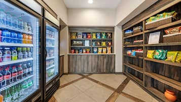 A snack and beverage area with refrigerated drinks, snack shelves, and a tiled floor.