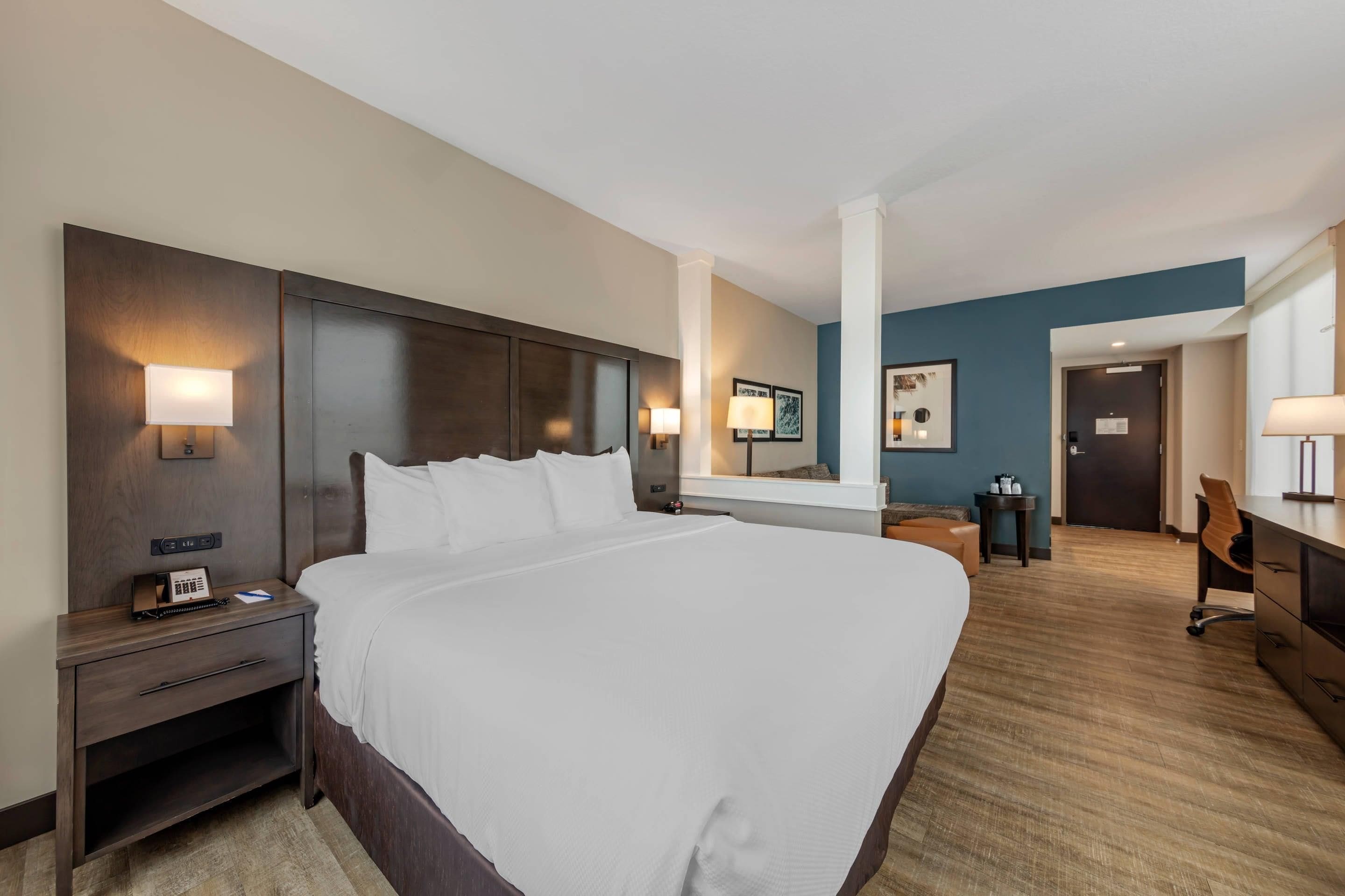 A hotel room with a large bed, bedside tables, a desk, and a chair.