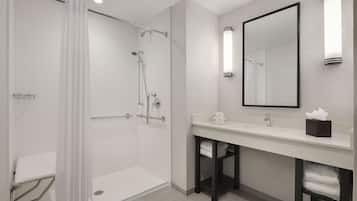 A modern bathroom with a walk-in shower, a toilet, a sink with a mirror, and a towel rack.