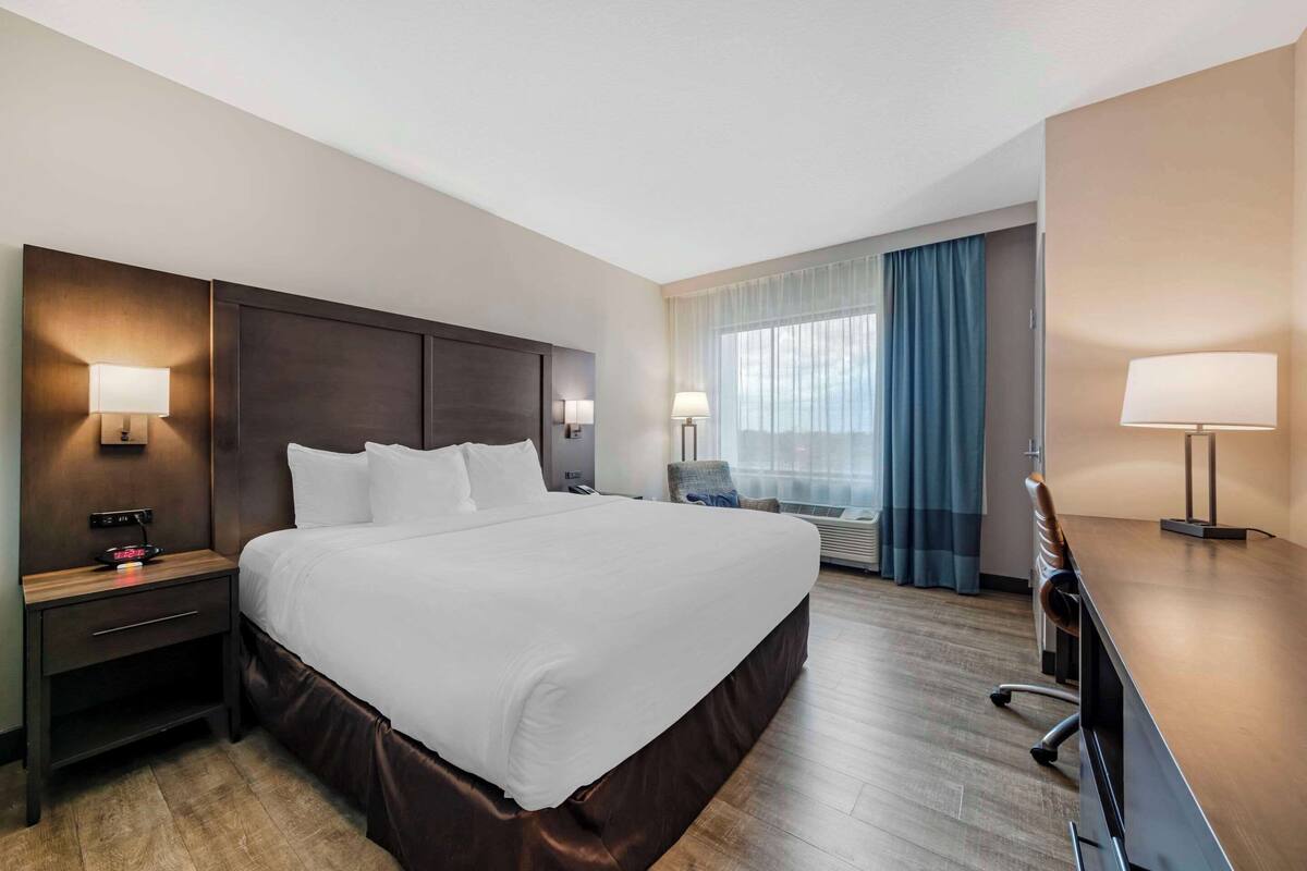 A hotel room with a large bed, bedside tables with lamps, a desk, and a chair.