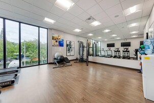 Un gimnasio espacioso con equipamiento de ejercicio, ventanas amplias y vistas al exterior.