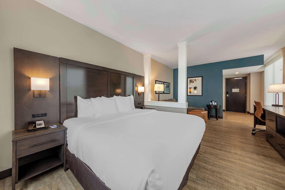 A hotel room with a large bed, bedside tables, a desk, and a chair.