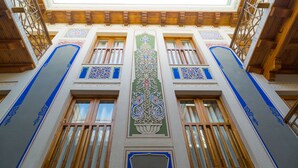 A building with ornate architectural details, including decorative patterns and wooden window frames. - Hotel Volida Boutique (Bukhara)