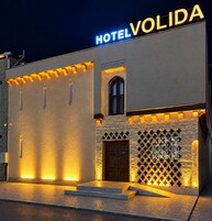 Un hotel llamado 'HOTEL VOLIDA' con una fachada moderna, una entrada destacada y una pared decorativa con cruces.