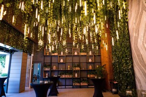 Un interior moderno con lámparas colgantes, estantes con objetos decorativos y plantas en macetas.