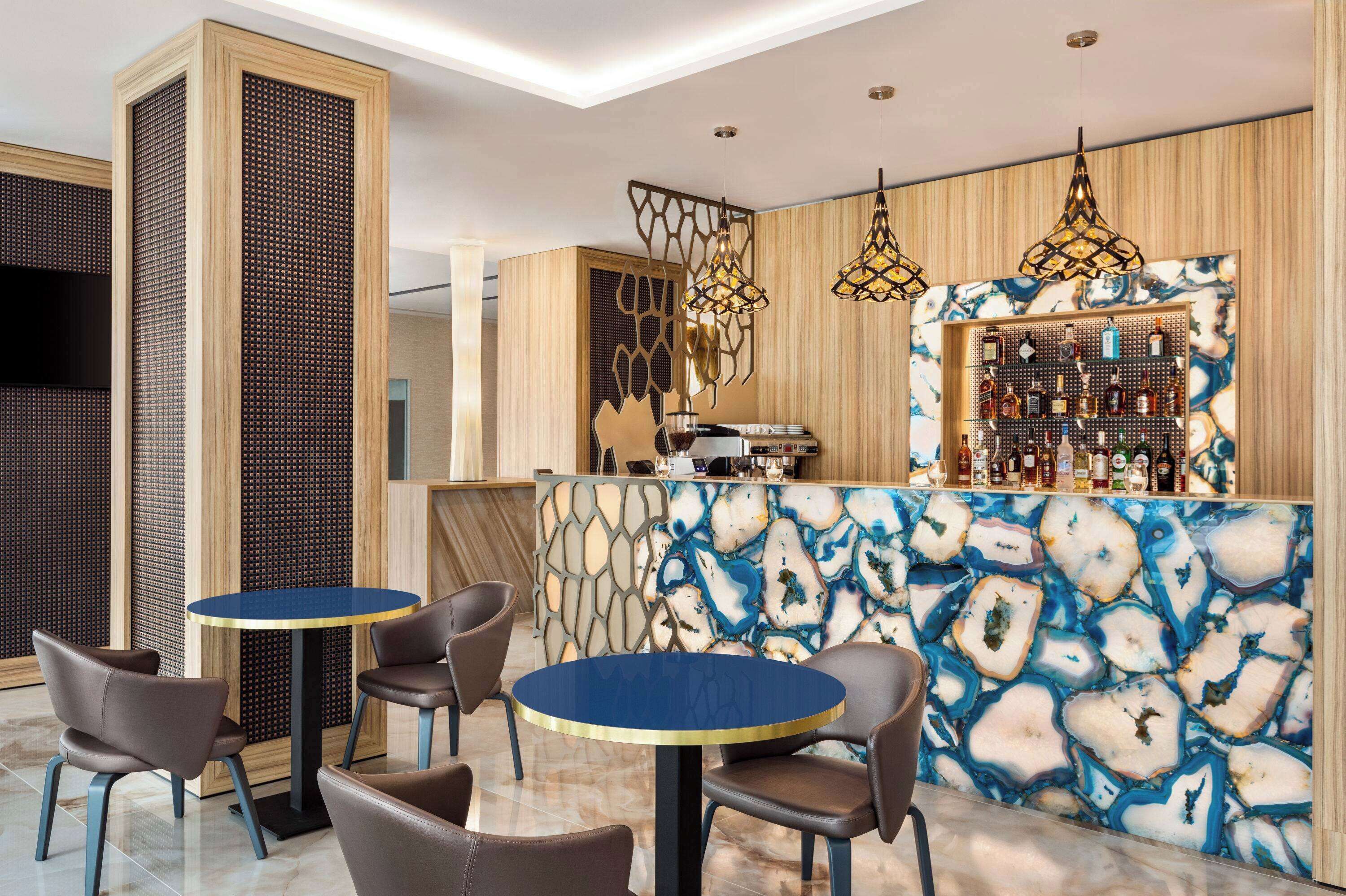 Eine moderne Bar mit Marmorplatte, hängenden Pendelleuchten und einer Auswahl an Flaschen.