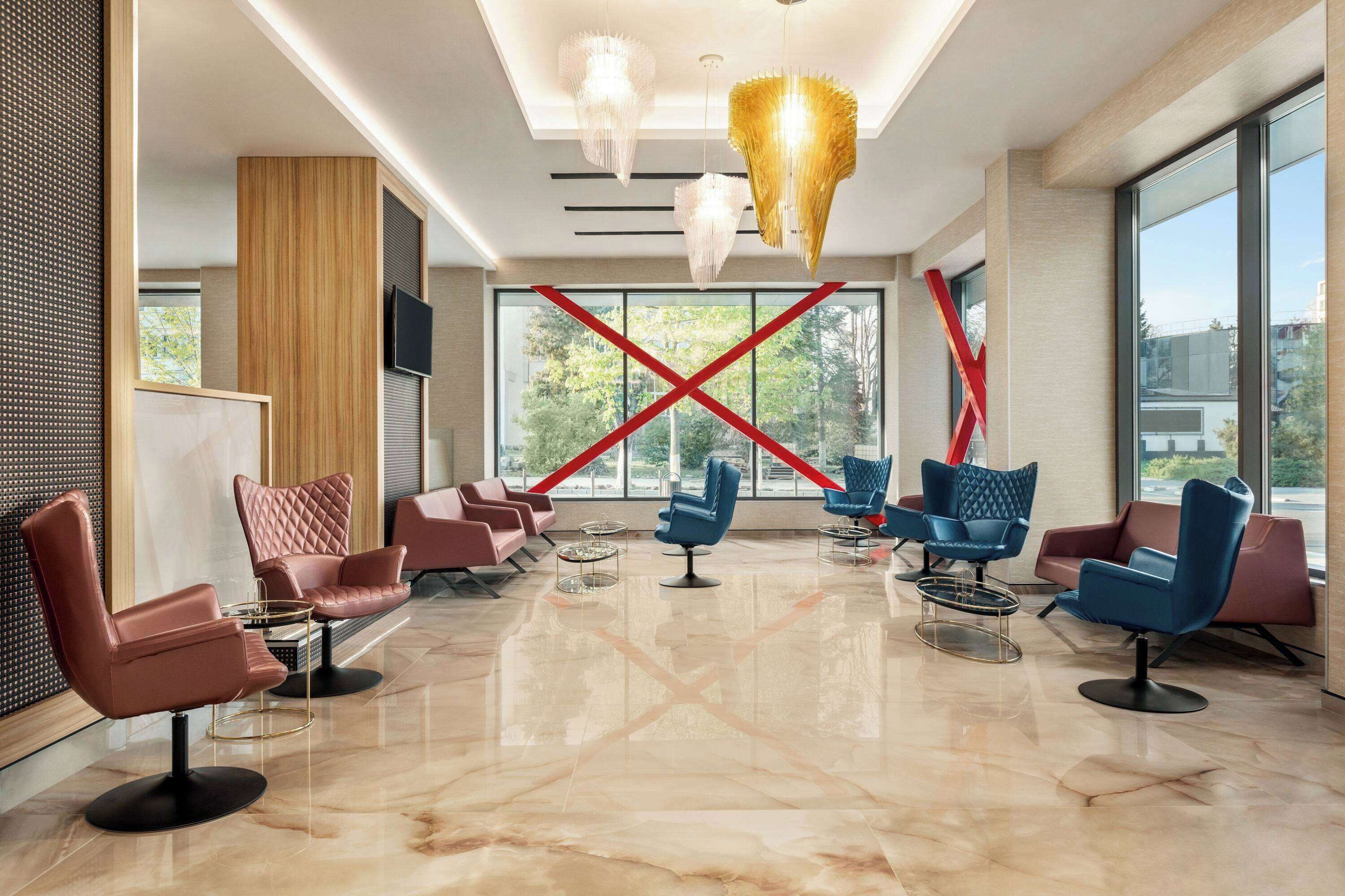 A modern lobby with leather chairs, a large window, and a unique chandelier.