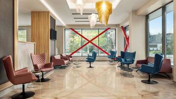 A modern lobby with leather chairs, a large window, and a unique chandelier.