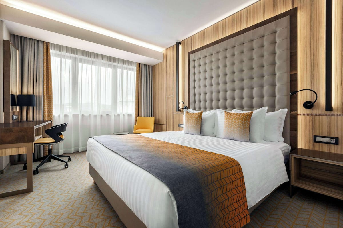 Une chambre d’hôtel avec un grand lit, un bureau, une chaise et une table de chevet.