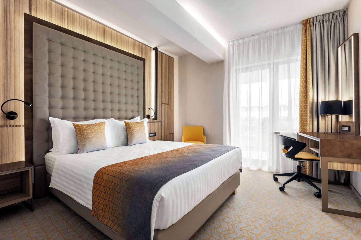 Une chambre d’hôtel avec un grand lit, un bureau et une chaise.
