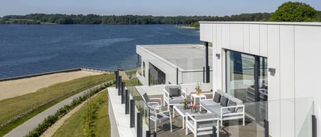 A modern building with a glass balcony overlooking a body of water.