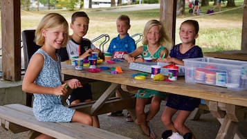 Children enjoy a fun outdoor activity at a picnic table amidst lush greenery.