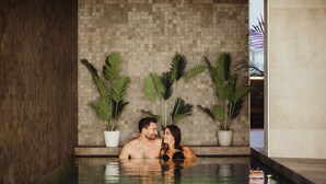 A couple in a small indoor pool with tiled walls and potted plants. - Golden Lakes Hotel (Froidchapelle)
