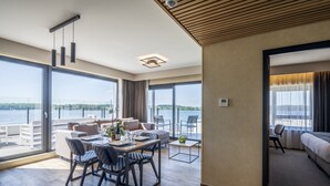 A modern hotel room with a balcony, a dining area, and a living space. - Golden Lakes Hotel (Froidchapelle)