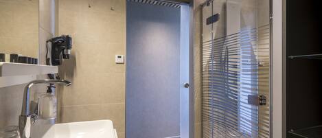 A modern bathroom with a sink, mirror, and shower area.