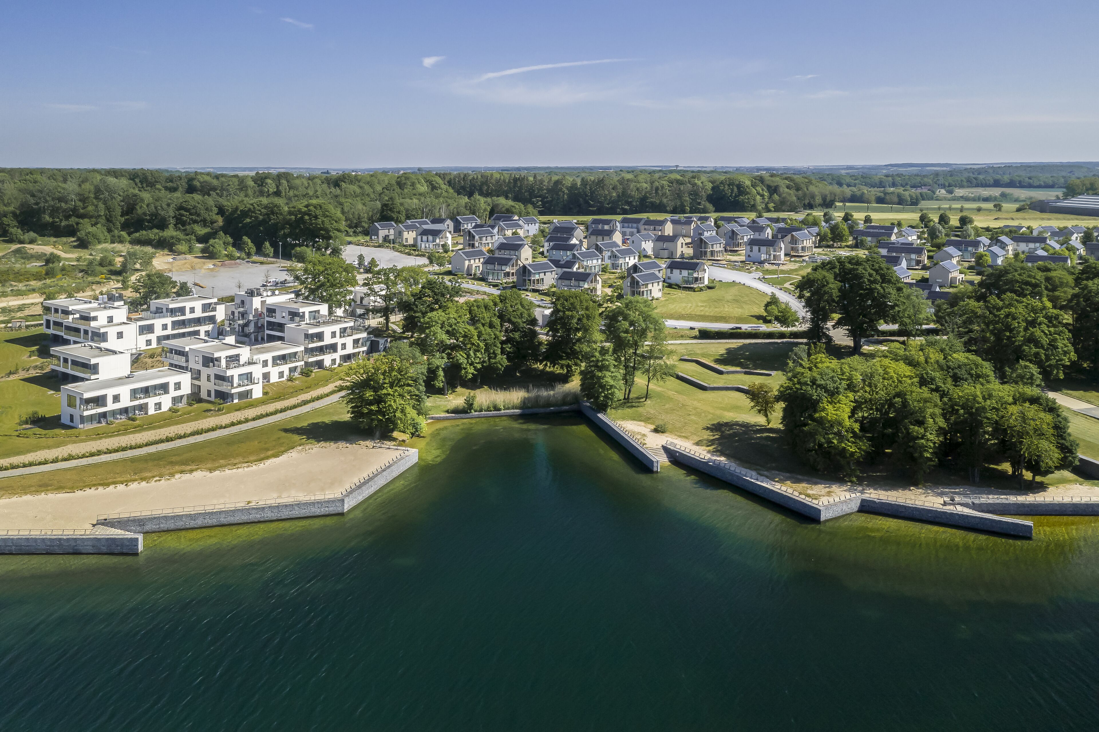A residential area with modern houses, a body of water, and a bridge.