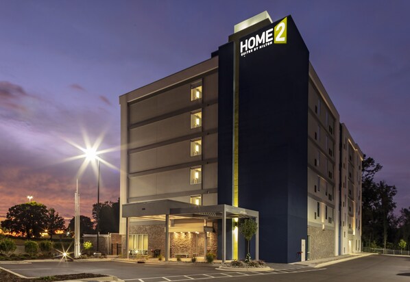 A multi-story hotel with a prominent 'HOME 2' sign, a covered entrance, and a parking area.
