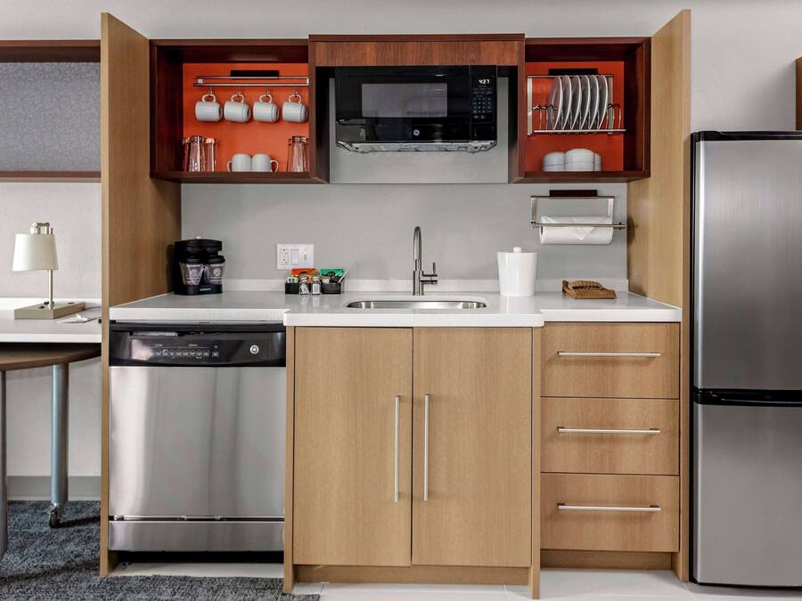 Eine kompakte Küche mit Geschirrspüler, Edelstahlkühlschrank und Holzausstattung.