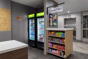 A reception area with a reception desk, two beverage dispensers labeled 'cold' and 'really cold', a vending machine stocked with snacks, and an elevator.