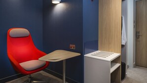 A modern hotel room with a red chair, a small table, and a wooden wardrobe. - Holiday Inn Express Wiesbaden by IHG (Wiesbaden)