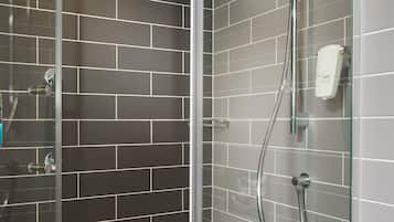 Ducha moderna con puerta de vidrio, cabezal de ducha manual y rociador de mano.