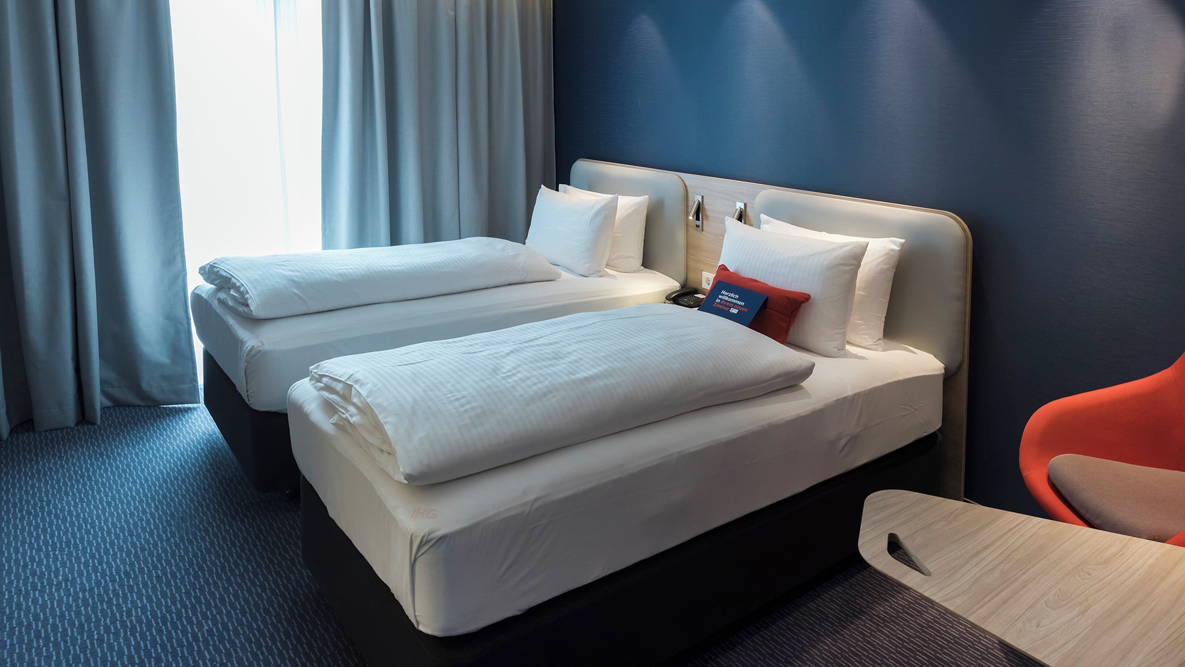 Habitación de hotel con dos camas, un escritorio y una silla.