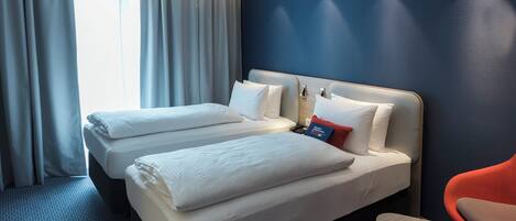 Habitación de hotel con dos camas, un escritorio y una silla.