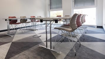 Une salle de conférence dotée d’une grande table, de nombreuses chaises et d’un sol recouvert de moquette.