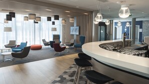 A modern bar area with stools, a counter, and a television screen. - Holiday Inn Express Wiesbaden by IHG (Wiesbaden)