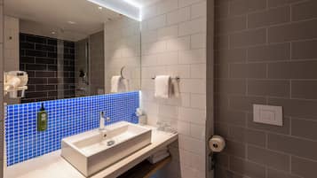 Ein modernes Badezimmer mit einem weißen Waschbecken, einer blauen Fliesenrückwand und einem Spiegel.