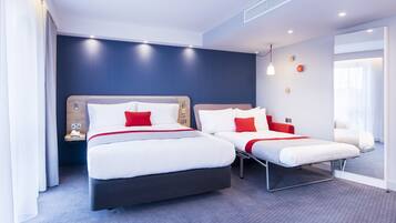 Ein Hotelzimmer mit zwei Betten, einem Nachttisch und einem großen Fenster.
