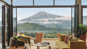 Una sala de estar moderna con un sofá, sillones y una mesa de centro, con un amplio ventanal y vistas a la montaña.