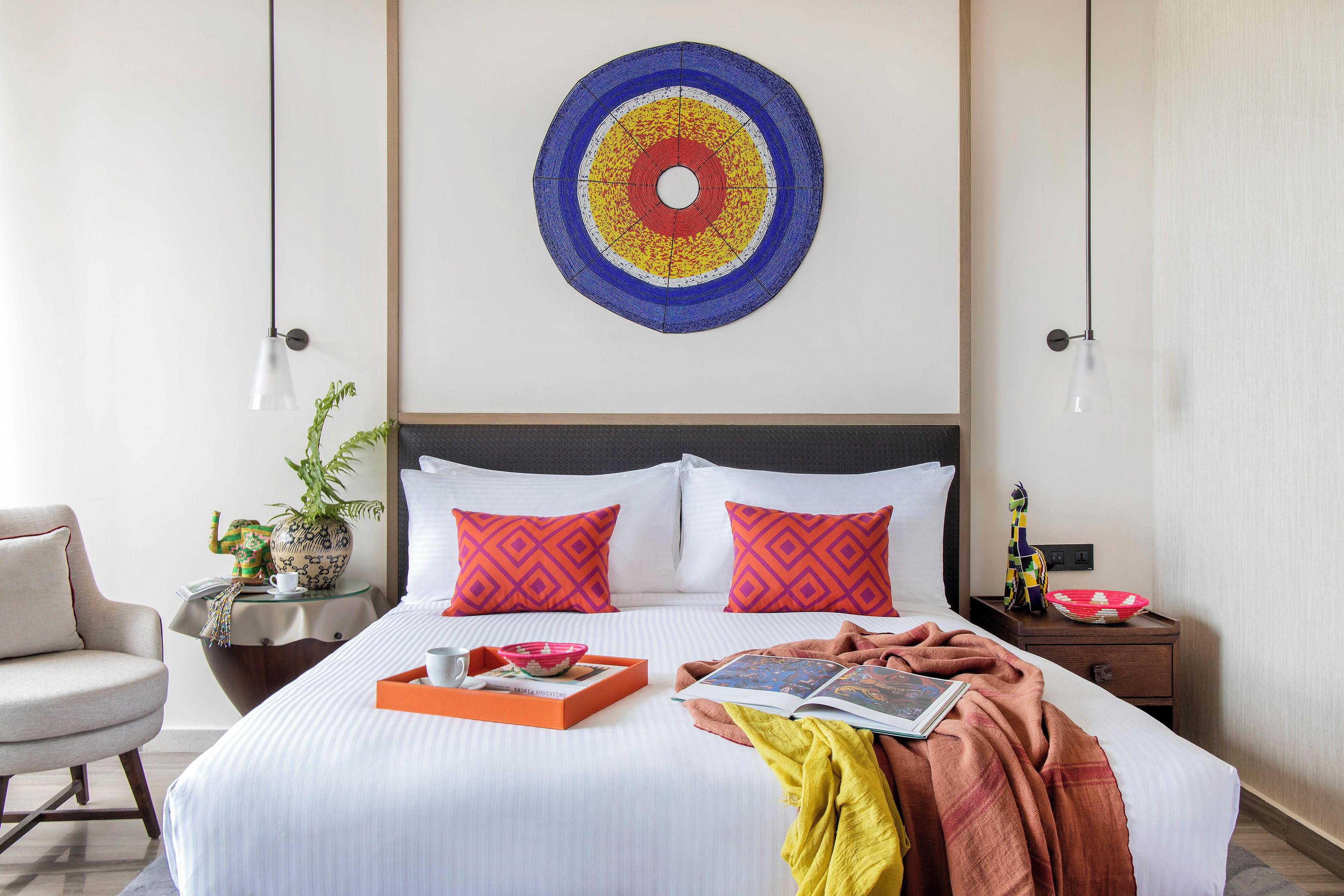 A neatly made bed with a tray of breakfast items, a book, and a blanket.